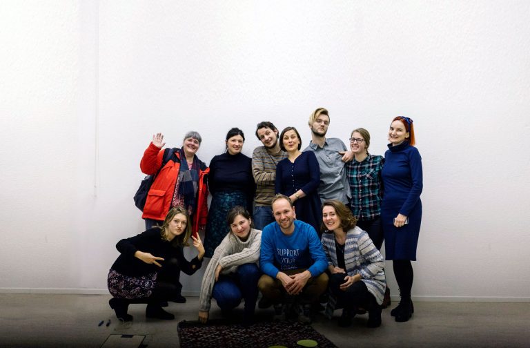 The whole team of the Theodor-Heuss-Kolleg Berlin office indoors in front of a white all